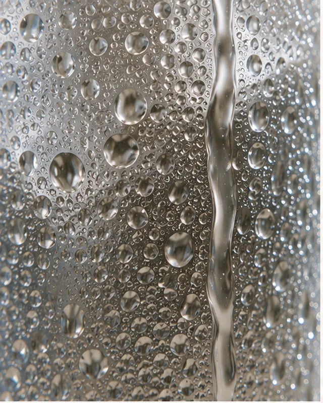 Macro detail of condensation droplets running down a cold glass surface.